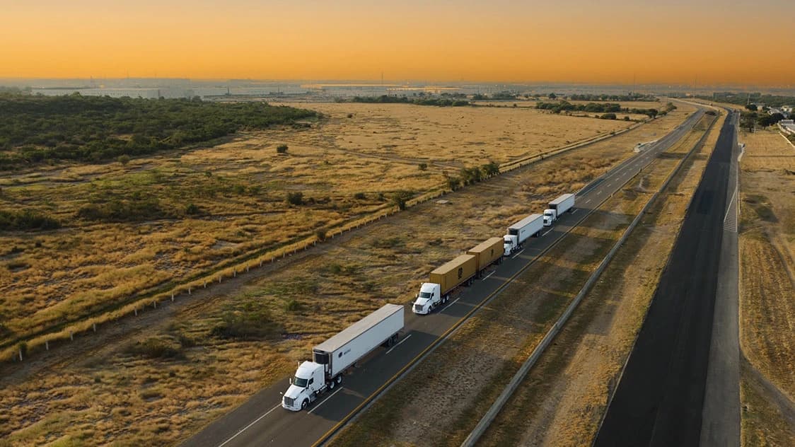 Vista aérea de convoy de tractocamiones TLM en autopista al atardecer